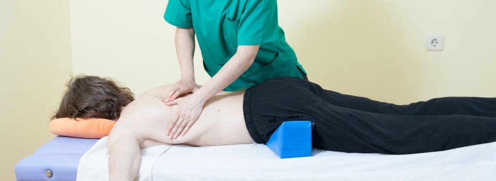 Fisioterapeuta tratando la zona dorsal y lumbar de un paciente en FisioBustar, Bustarviejo